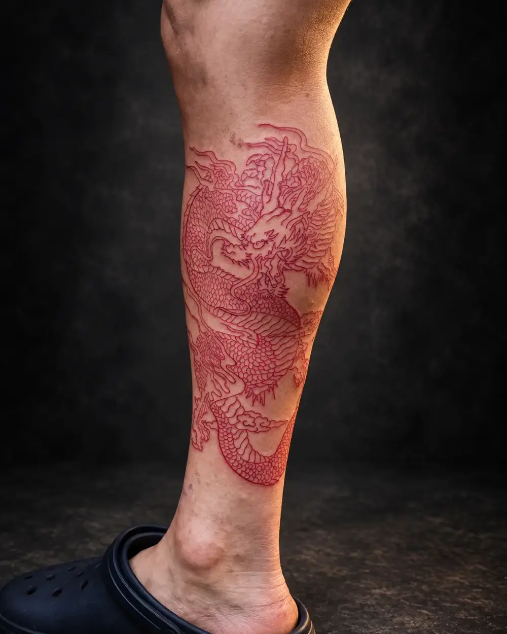 Tatuaje de dragón rojo fine line en la pierna por Lucca Haro, tatuador en Buenos Aires (CABA)