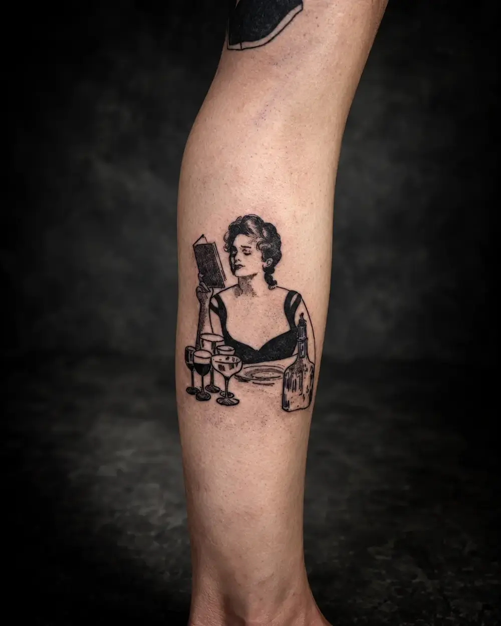 Tatuaje de mujer en la mesa con copas de vino en la pantorrilla por Lucca Haro, tatuador en Buenos Aires (CABA)