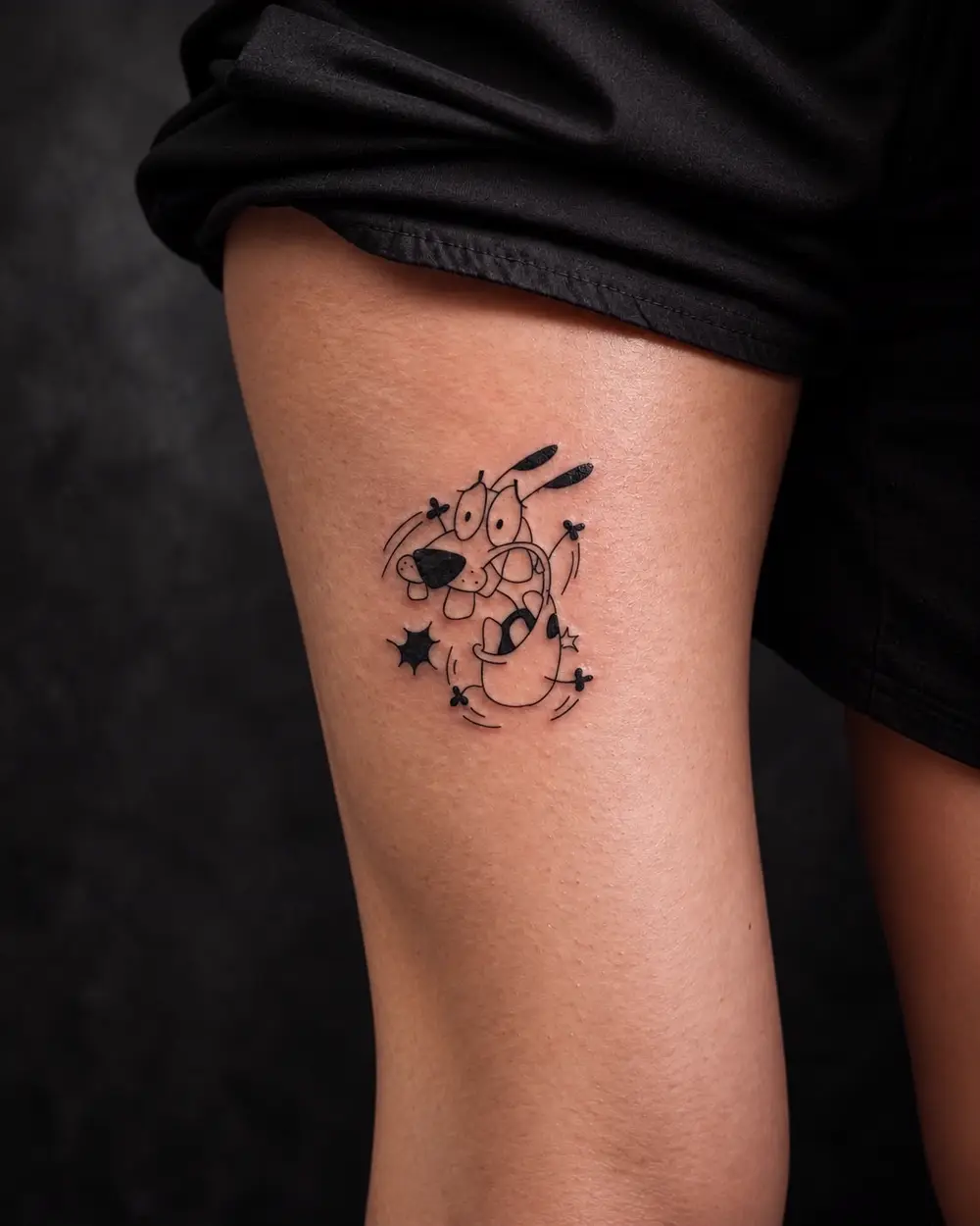 Tatuaje fine line de Courage el perro cobarde con estrellas en el muslo por Lucca Haro, tatuador en Buenos Aires (CABA)