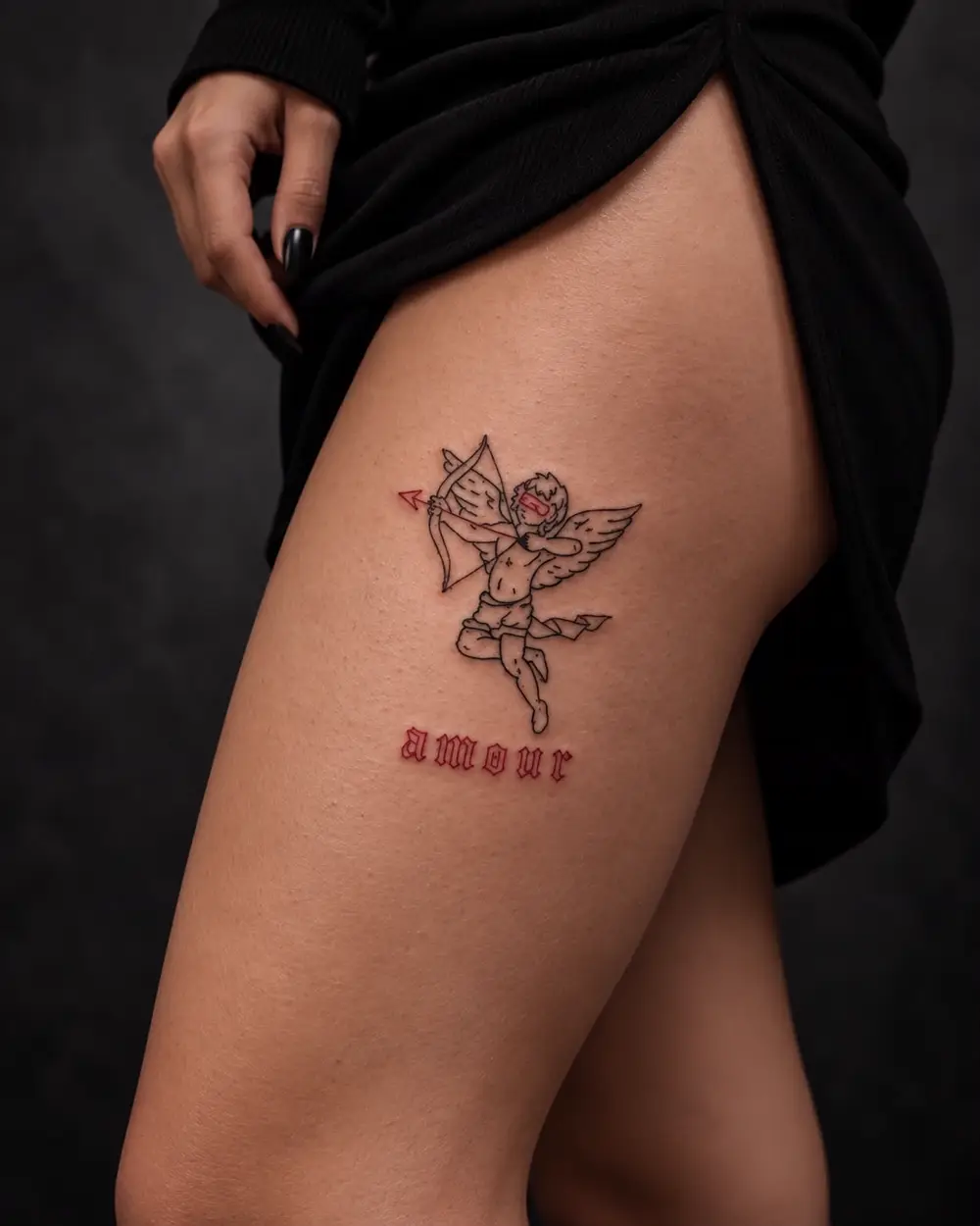 Tatuaje fine line de querubín cyber con arco y la palabra amour en el muslo por Lucca Haro, tatuador en Buenos Aires (CABA)