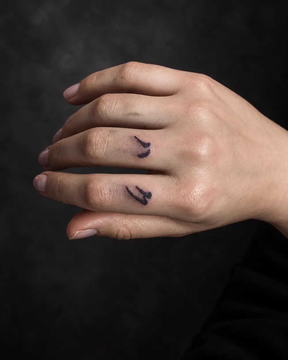 Tatuaje blackwork de marcas caligráficas en los dedos por Lucca Haro, tatuador en Buenos Aires (CABA)